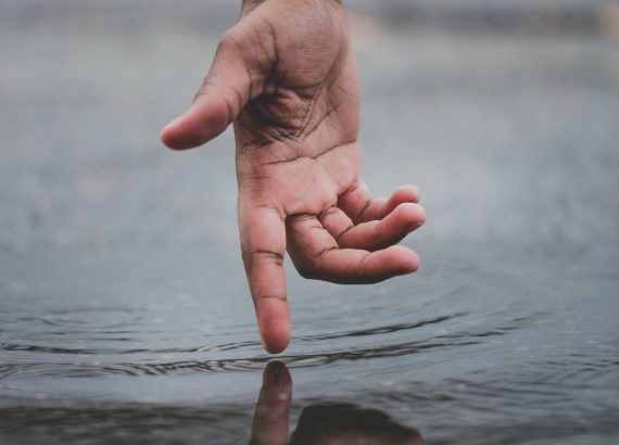 Person touching body of water and causing ripples